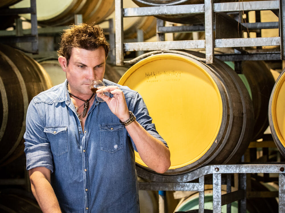 Mark inspecting some product with rum barrels in the backdrop