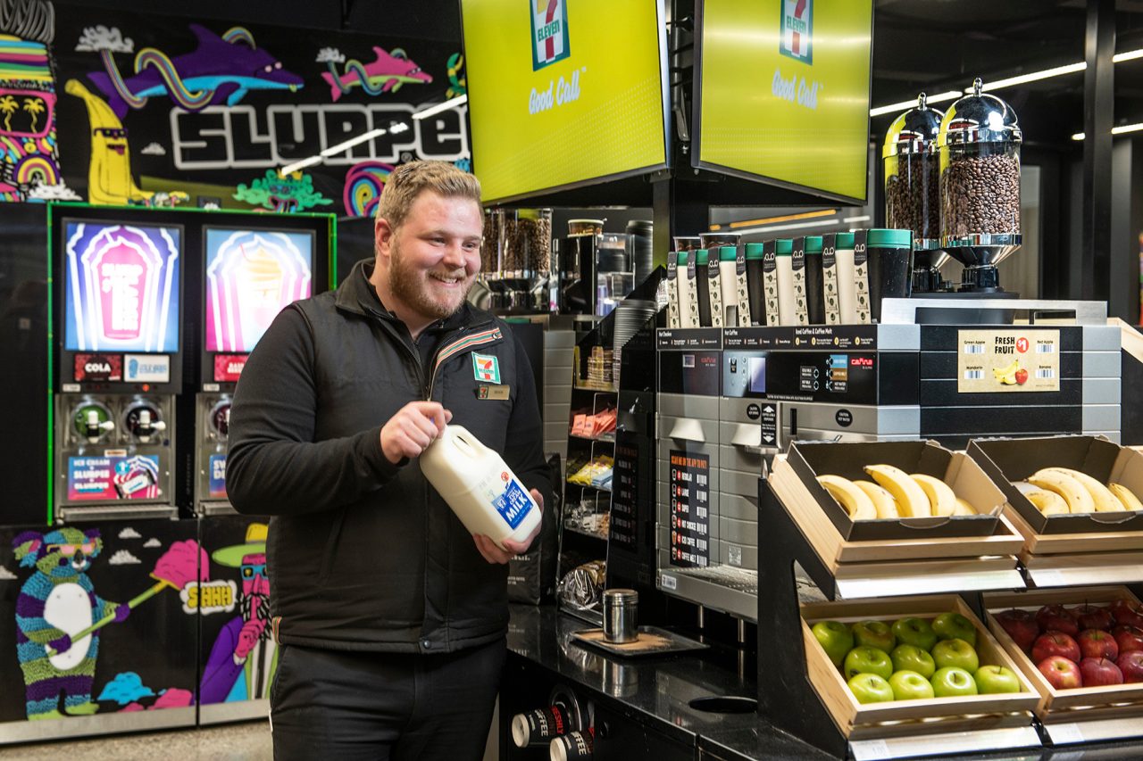 A 7-Eleven store worker holding a bottle of milk