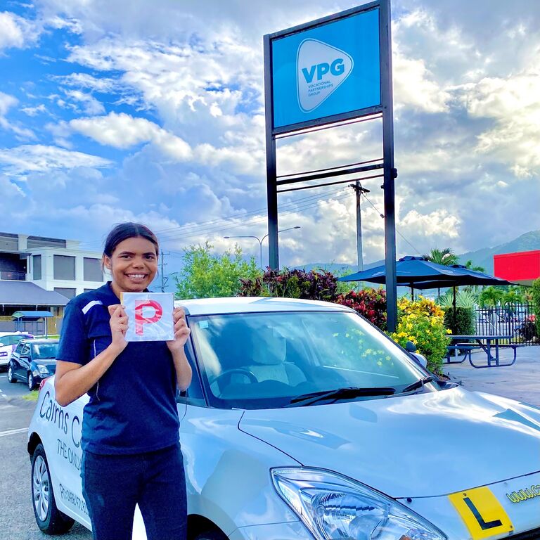 Youth Trainee Worker, Cedella, has also received her P plates with the help of VPG's Learner Driver Program. Pictured is Cedella holding a P plate in front of a white car. 