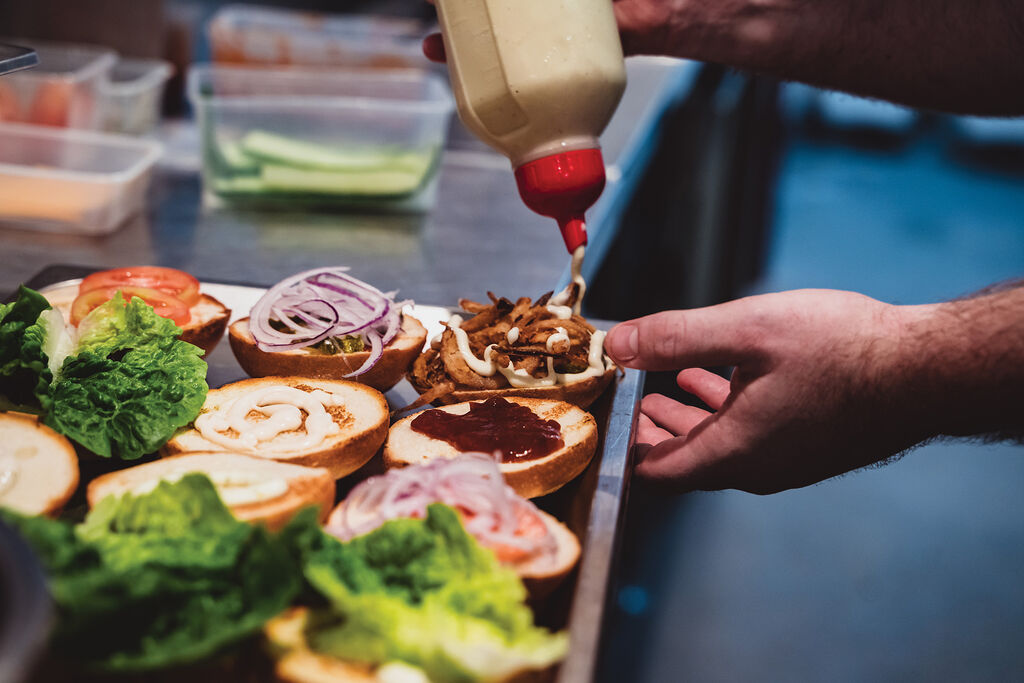 A close-up shot of burgers being constructed in the kitchen 