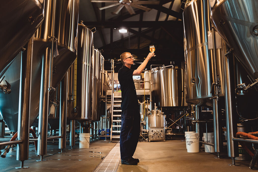 Head brewer Nico Leffler holding up a glass of beer to the light in the brewery