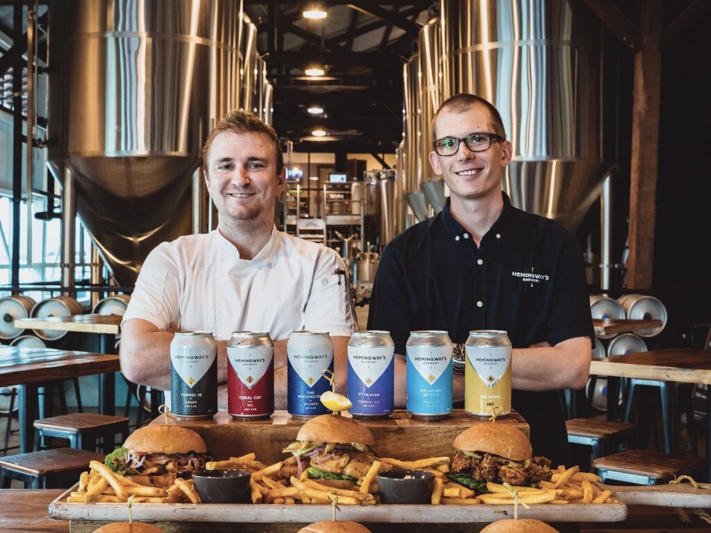 Hemingway's Reid Brydon & Nico Leffler posing behind a display of beers and burgers